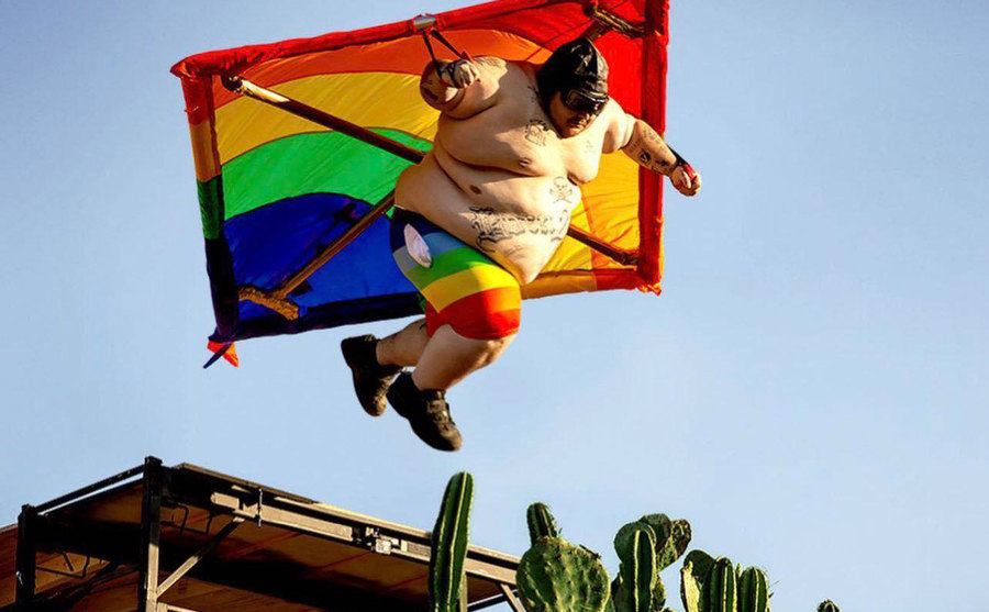 A man attached to a kite jumping off a hill. 