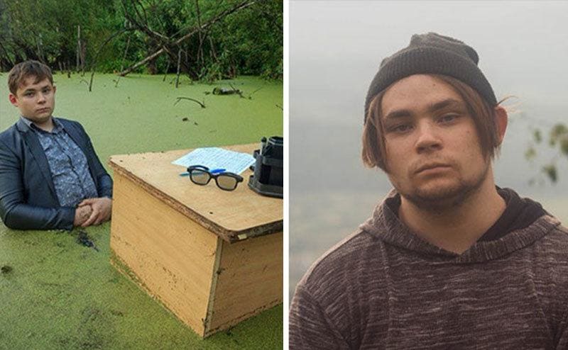 A serious Teenage-Russian kid stands inside a swamp behind a desk / Igor Nazarov wears a severe look.