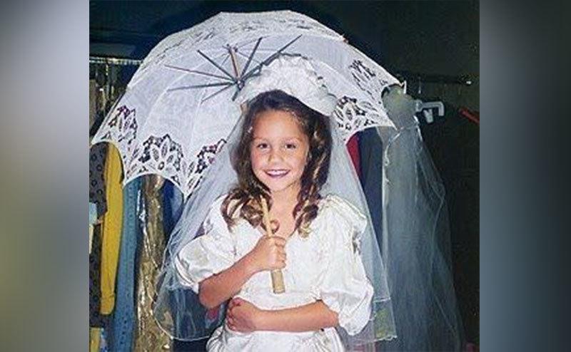 A young Amanda Bynes plays dress-up in a white dress.