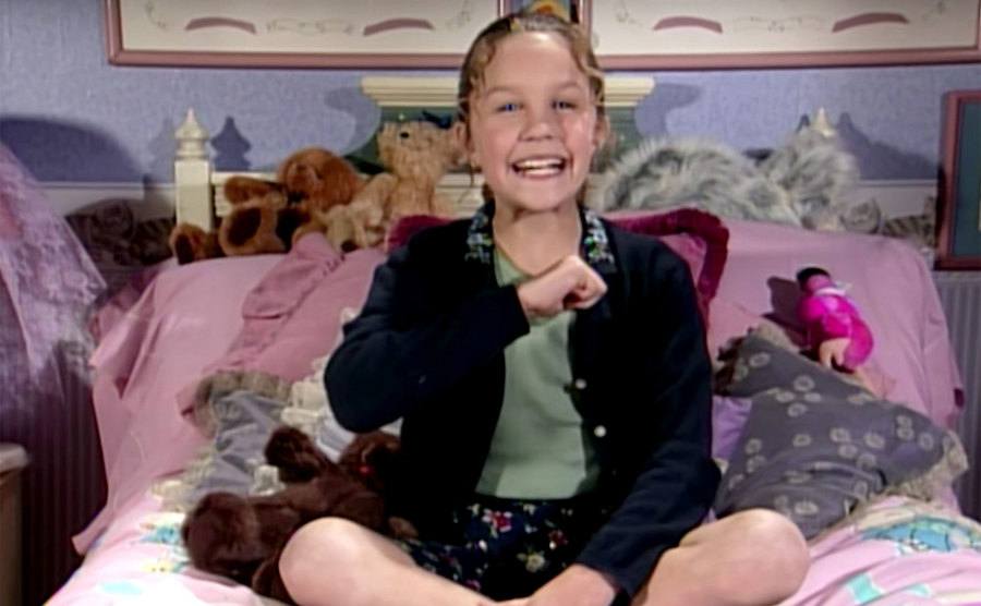 Bynes sits on a bed in a segment from “All That” called “Ask Ashley.”