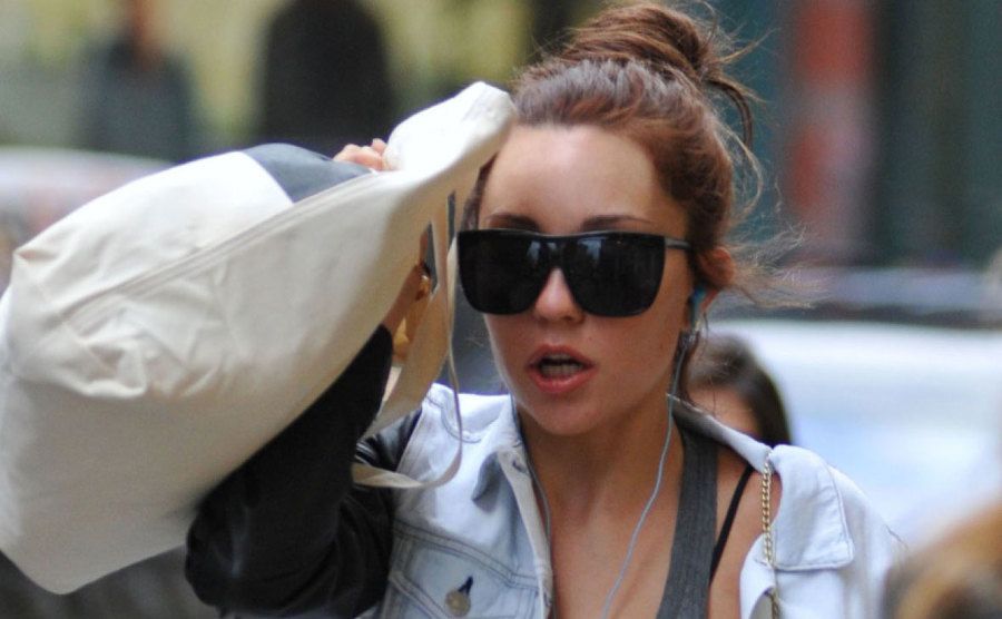 Amanda Bynes tries to cover her face with her bag as she walks down the street.