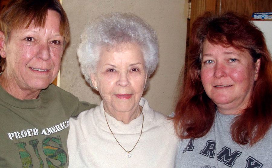An elderly Betty takes a picture with her daughters.