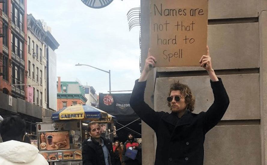 A man is holding a sign that reads ‘’Names are Not that Hard to Spell.’’