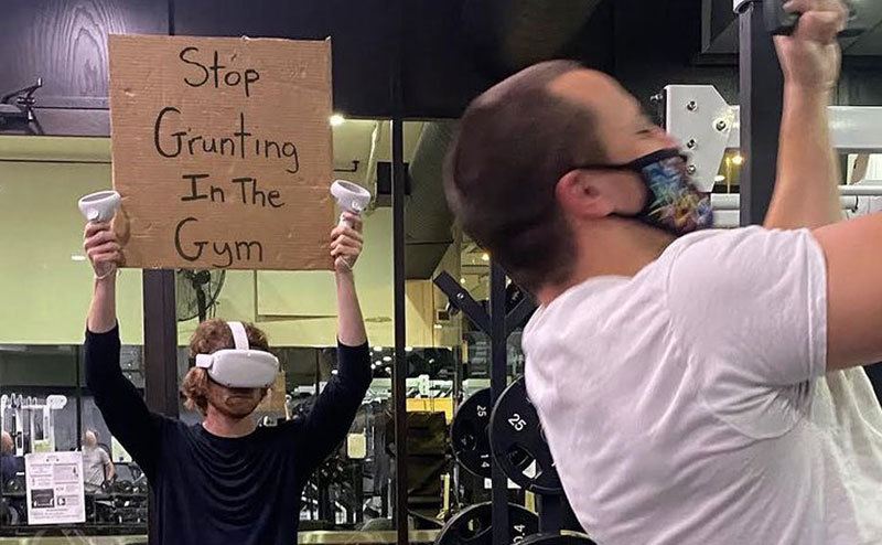 A man is holding a sign that reads ‘’Stop Grunting in the Gym.’’
