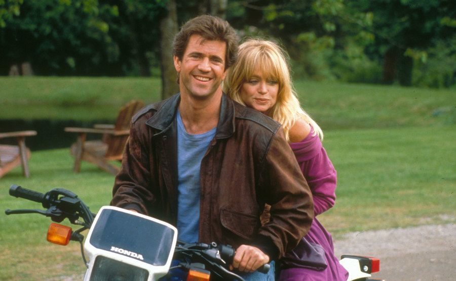 Goldie Hawn and Mel Gibson sit on a motorcycle in a still from Bird on a Wire.
