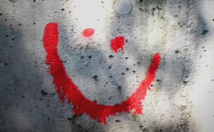 A smiley face is spary painted on a wall.