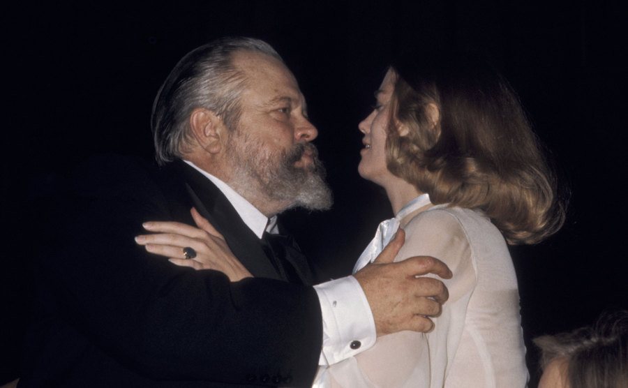 Orson Welles and Cybill Shepherd greet each other.
