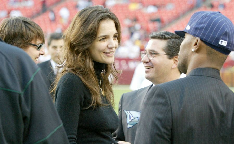 Tom Cruise, Katie Holmes, and Jamie Foxx greet each other during a game.