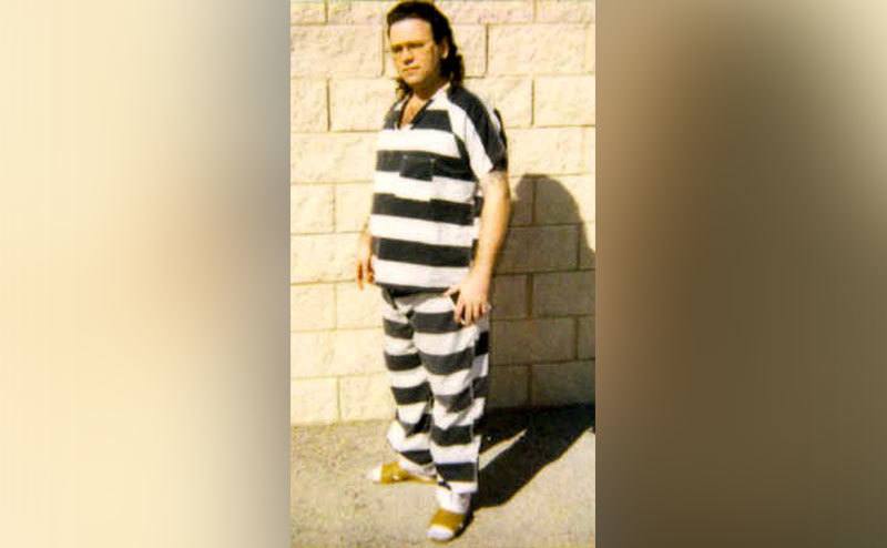 Tommy Sells stands in his prison jumpsuit. 