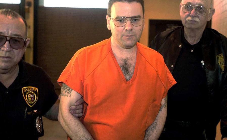 Tommy Sells, in handcuffs, is escorted by officers. 