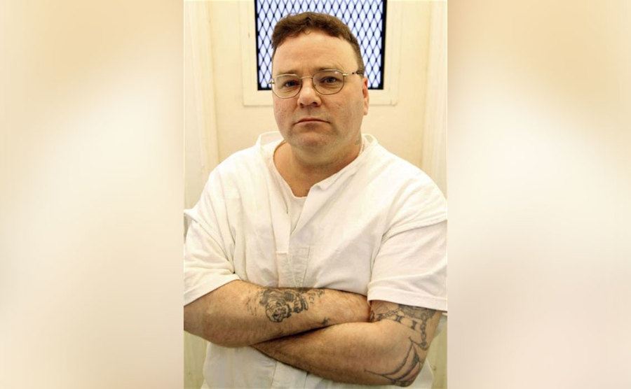 Sells stands with his arms crossed in prison. 