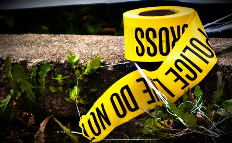 A roll of police tape ties on the ground outside the home.