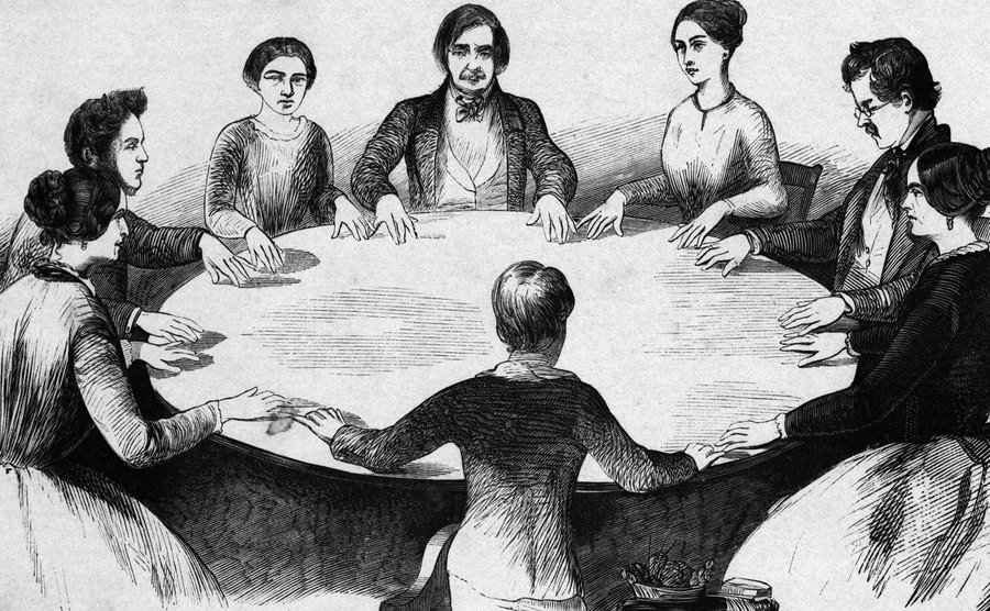 An illustration of a table rapping with the Fox Sisters.