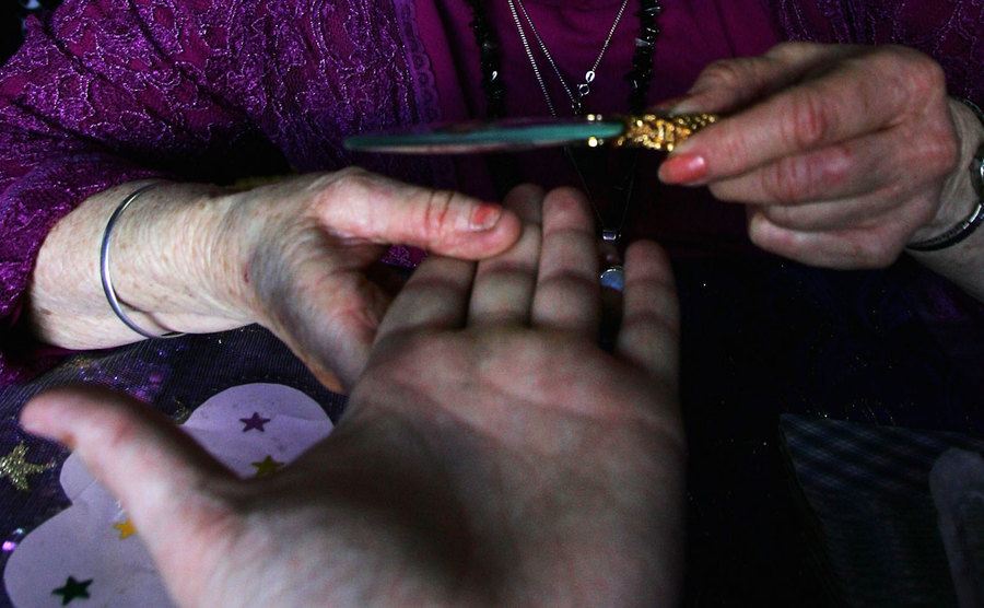 A fortune teller is reading a palm.
