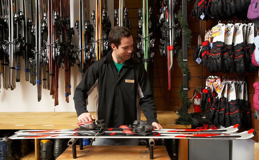 A man makes adjustments to a pair of skis.