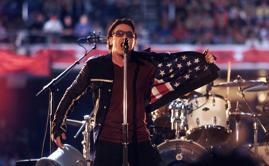 Bono flashes an American flag on the inside of his jacket during the Super Bowl XXXVI.