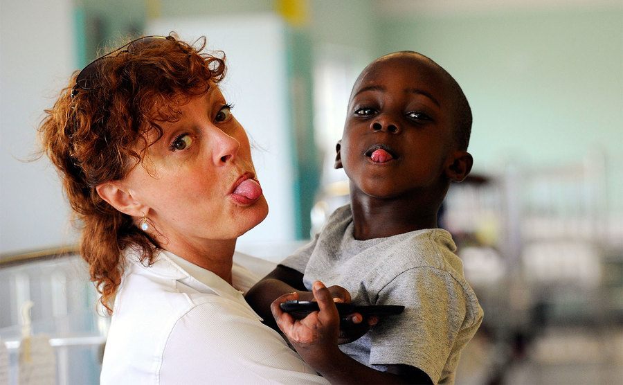 Susan Sarandon and a young Haitian boy make faces to the camera.