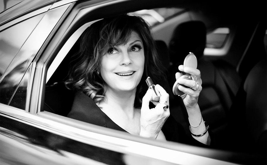 Sarandon reapplies her lipstick in the car.