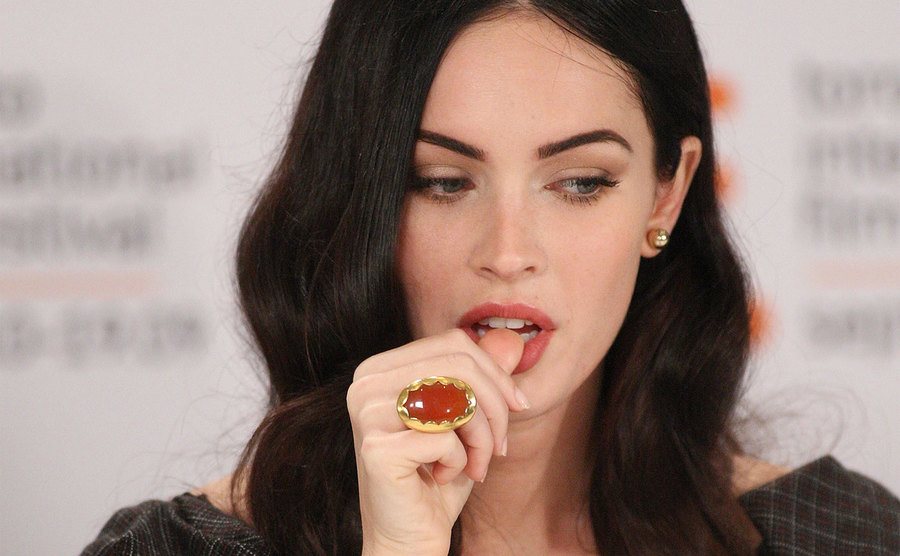 Fox nibbles on her thumb during a press event.