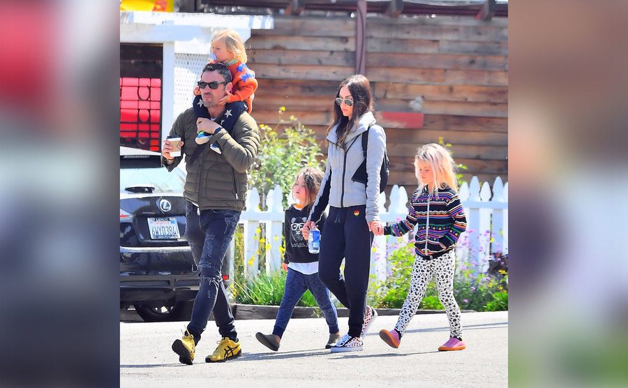 Megan and Brian walk down the street with their kids.