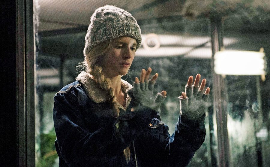Brit Marling, as Prarie Johnson, stands in a glass cage.