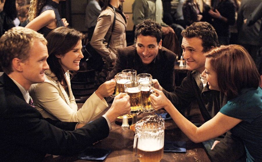 Barney, Robin, Ted, Marshall, and Lily sit in their booth at McLaren’s bar.