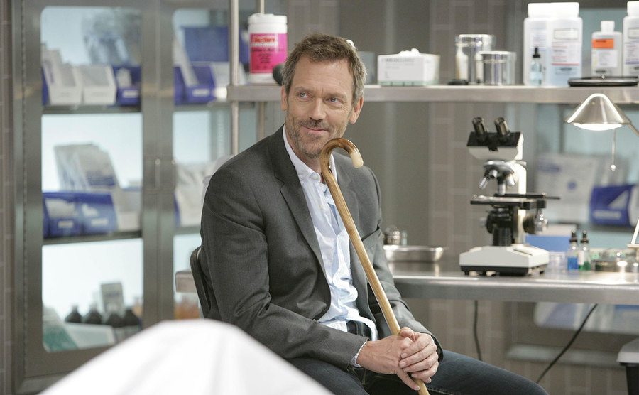 Hugh Laurie, as Gregory House, sits in a hospital lab.