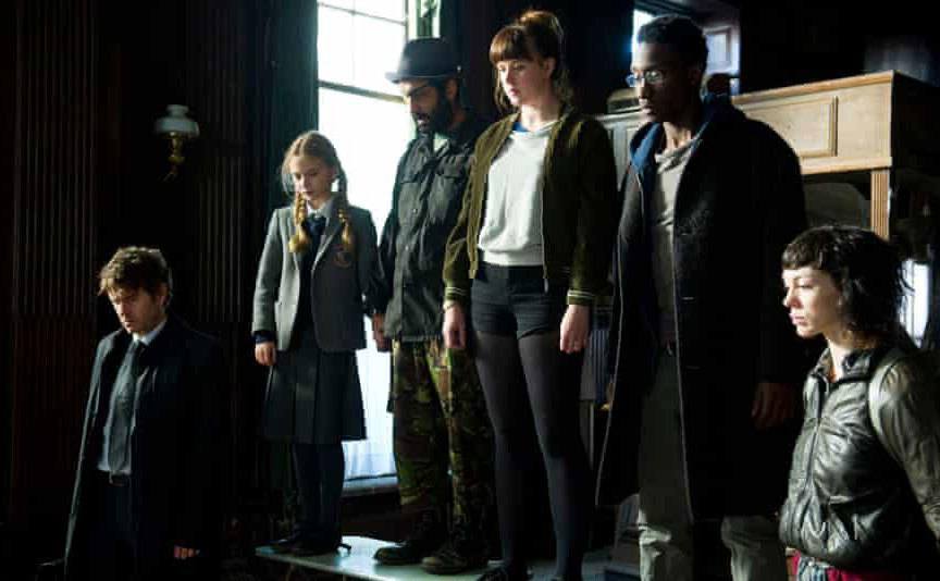 The cast of Utopia stare intently at something in a scene from the show.
