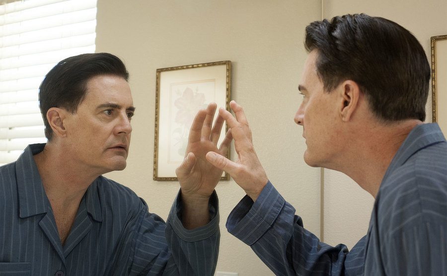 Kyle MacLachlan, as Dale Cooper, stares at himself in the mirror.
