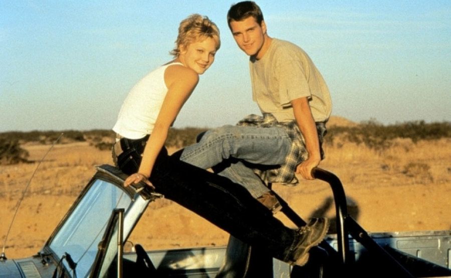 Drew Barrymore and Chris O'Donnell sit on top of their jeep in a still from Mad Love.