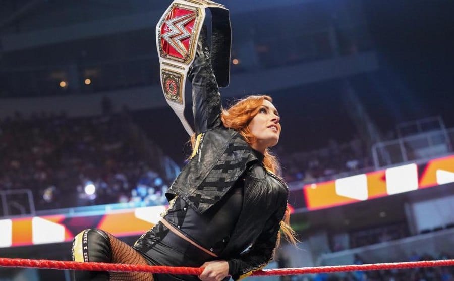 Becky Lynch waves her championship belt over her head.