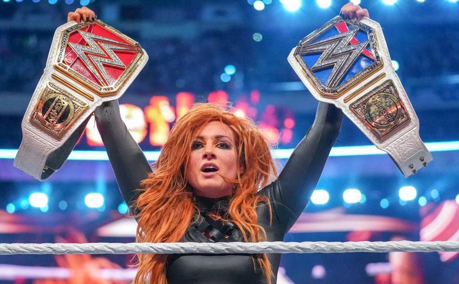 Becky Lynch hoists up her two winning belts at the end of the match.
