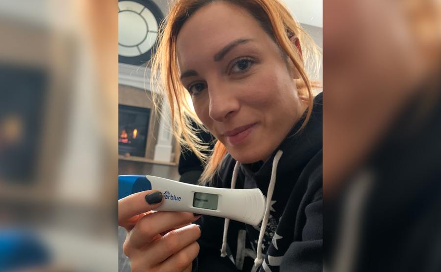 Becky takes a selfie with her positive pregnancy test.