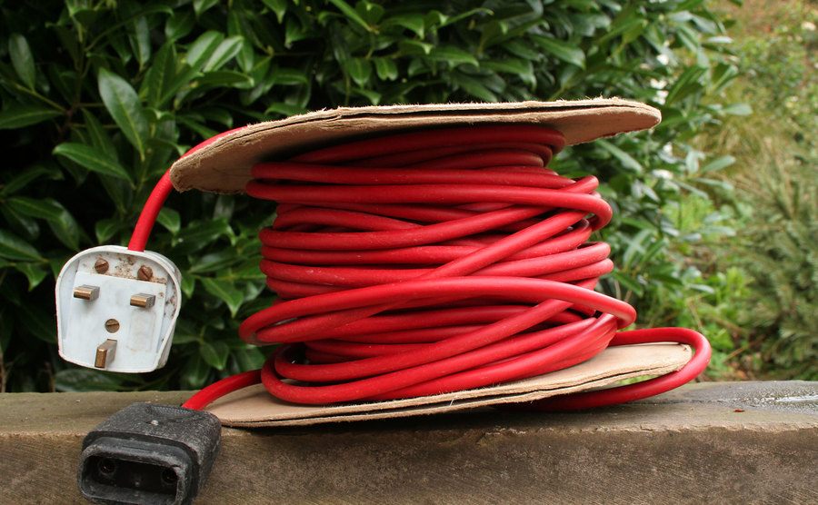 An image of an extension cable next to a garden wall.