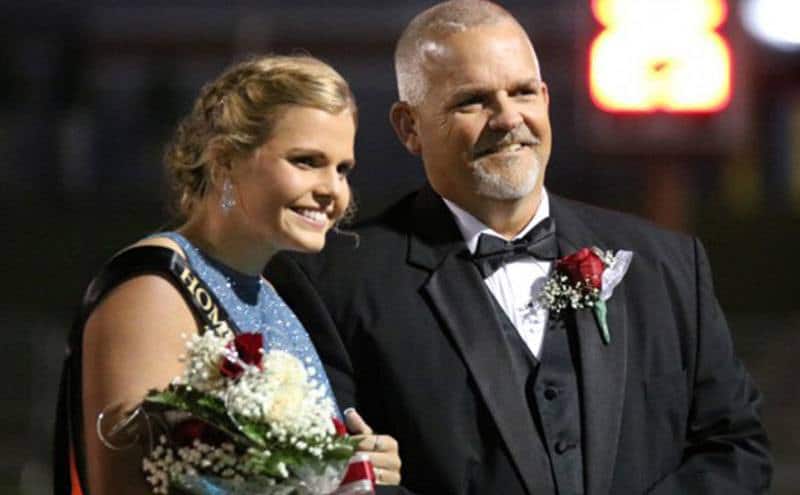A member of the homecoming court poses with her father.