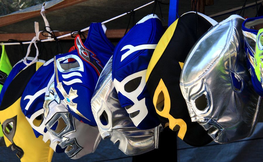 A group of luchador masks hangs out on display.
