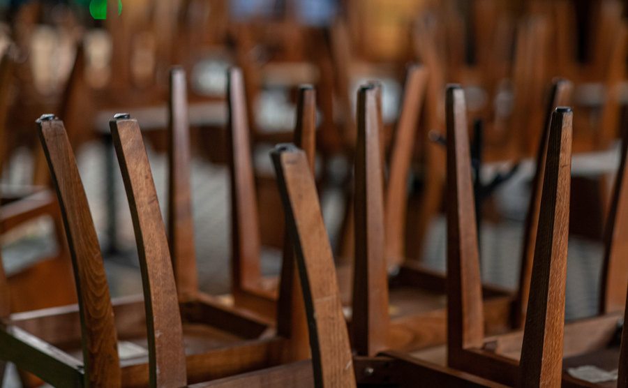 A picture of a closed restaurant and chairs flipped over on the tables.