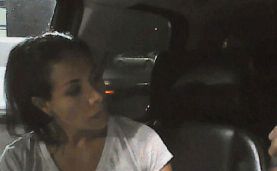 A picture of Lulu in her car staring at her phone.