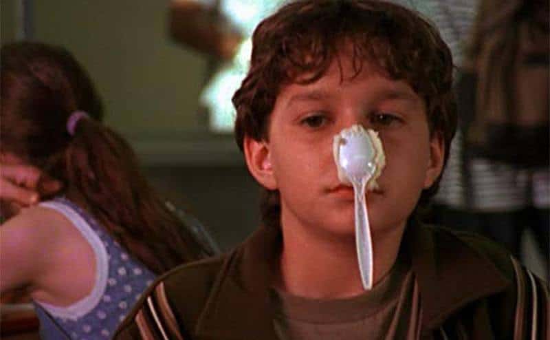 A young Shia balances a spoon on his nose. 