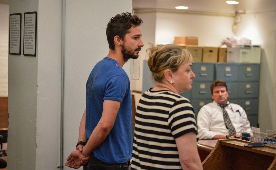 Shia LaBeouf stands in handcuffs during his arraignment in court. 