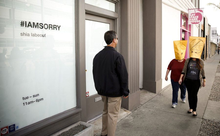 Two girls with paper bags on their heads get in line to see LaBeouf.