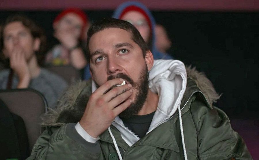 Shia LaBeouf is eating popcorn in the movie theater. 