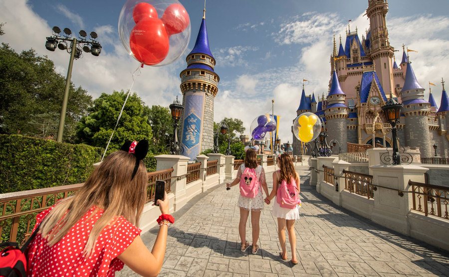 Tourists take pictures as they enter the Magic Kingdom.