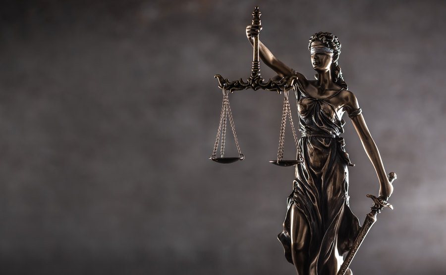 A blind justice symbol on a metallic statue on a dark background.