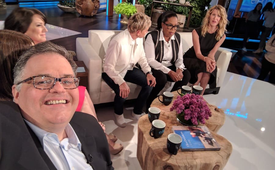 David Higgins taking a selfie on the Ellen DeGeneres show while sitting with Joely Fisher, Ellen, Oprah, and Laura Dern