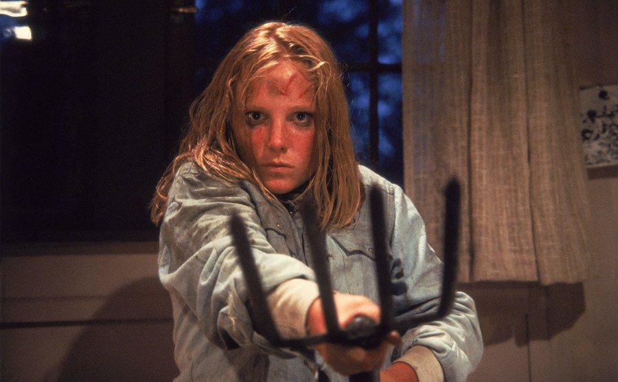 Ginny Field holds up a rake for protection.