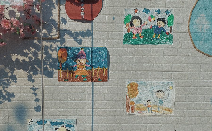 An image of kids’ drawings on a school wall.