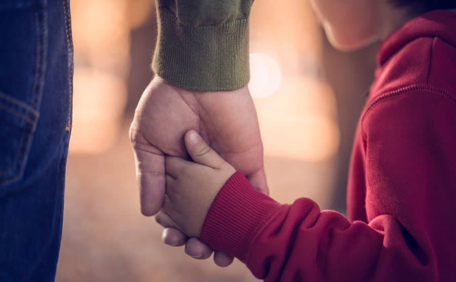 A father holds his son’s hand.