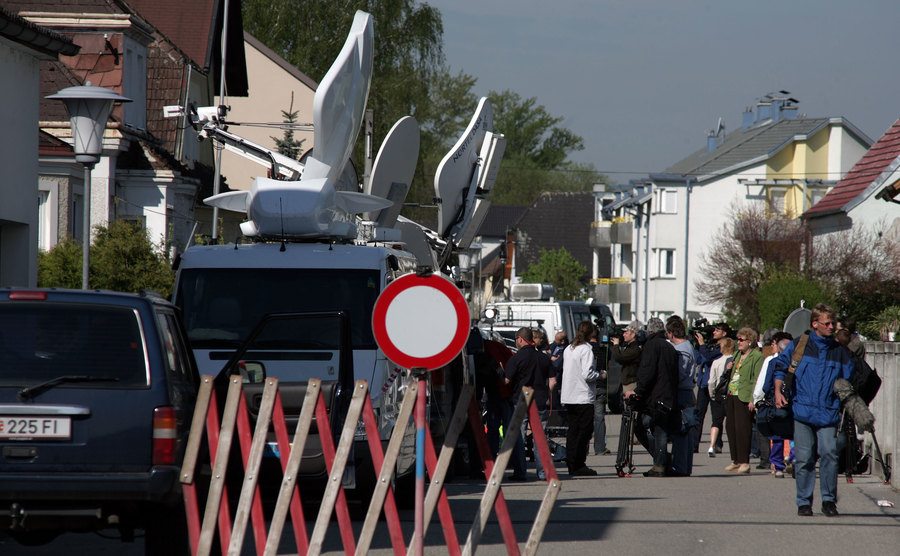 An image of broadcast vans and journalists crowding a street beside the Fritzl house.
