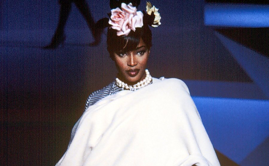 A dated image of Naomi Campbell walking the runway of a fashion show.